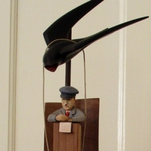 Fotografie einer Skulptur. Ein Vogel trägt einen Korb, in dem ein Mann sitzt.